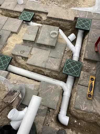 Drainage pipes and catch basins installed beneath a paver patio