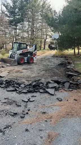 Skid steer removing torn-out asphalt from an old driveway