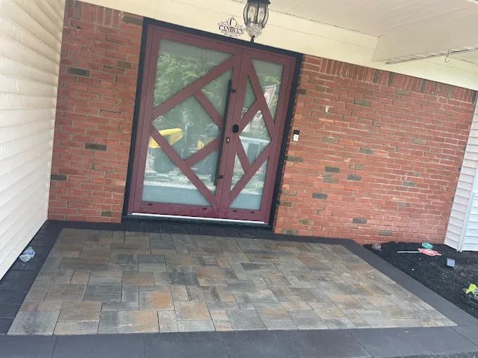 Crew raking fresh asphalt on a residential driveway by an open garage
