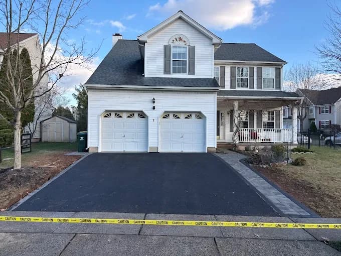 Smooth black asphalt driveway with paver border at a two-story suburban home