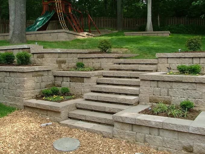 Multi-tier retaining wall with wide stone steps and built-in planters
